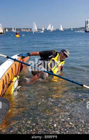 Uomo in camicia di vita di cadere fuori del kayak in spiaggia durante la barca di legno Festival, Port Townsend, Washington, Stati Uniti d'America Foto Stock