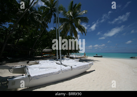 Una tipica scena di spiaggia nelle Maldive, due catamarani al di fuori della scuola di vela Foto Stock