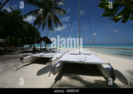 Una tipica scena di spiaggia nelle Maldive, due catamarani al di fuori della scuola di vela Foto Stock