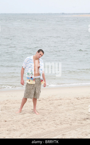 Un giovane uomo in piedi sulla spiaggia a piena lunghezza ritratto Foto Stock