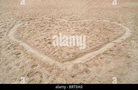 A forma di cuore scolpito in spiaggia di sabbia Foto Stock