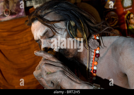 Un Naga Sadhu di fumare il suo chillum. Foto Stock