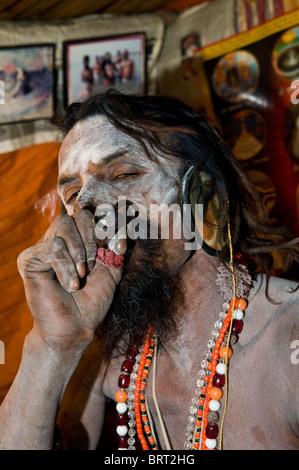 Un Naga Sadhu di fumare il suo chillum. Foto Stock