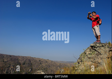Uomo con t-shirt rossa sulla cima di una montagna contro un cielo blu in Saia Brava riserva naturale, Vale do Côa, Portogallo Foto Stock
