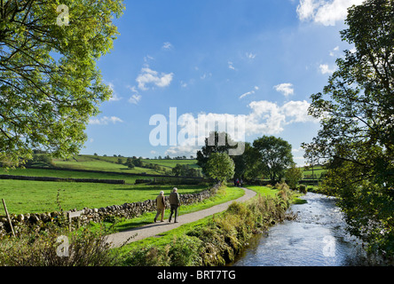 Coppia di anziani camminare al fianco di Malham Beck nel villaggio di Malham, Wharfedale, Yorkshire Dales National Park, England, Regno Unito Foto Stock