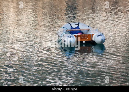 Piccola barca galleggiante in acqua calma a Clovelly Harbour in North Devon Regno Unito Foto Stock