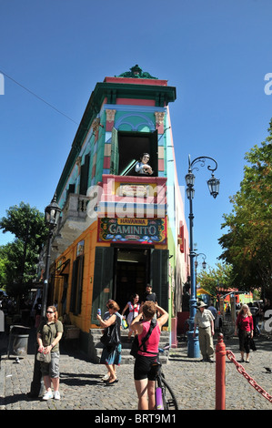 Ragazza in bicicletta a fotografare le strette Cafe Havanna, con una finestra superiore immagine di Maradona, Caminito, La Boca, Buenos Aires Foto Stock