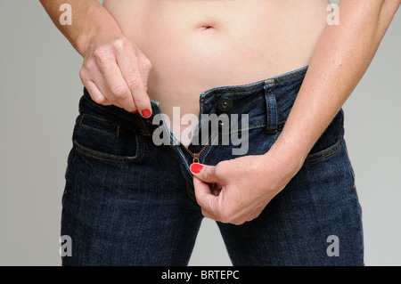 Donna tirando la zip sul suo jeans fino Foto Stock