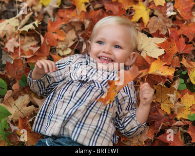 Felice anno due vecchia ragazza distesa su albero caduto le foglie in autunno la natura Foto Stock