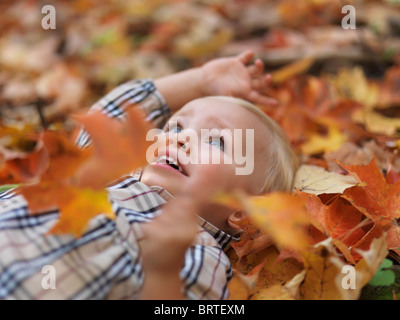 Due anni di ragazza distesa su albero caduto le foglie in autunno la natura Foto Stock