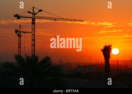 Gru da cantiere su arancione tramonto Cielo Foto Stock