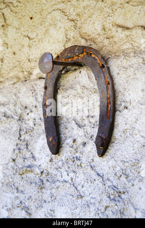 Ferro di cavallo arrugginito appesi ad un chiodo su una parete Foto Stock