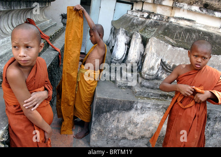 Khmer giovani monaci buddisti stanno mettendo su loro arancione vesti prima di una cerimonia in un tempio in Phnom Penh Cambogia.. Foto Stock