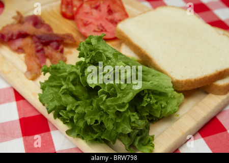 Bacon, lattuga, pomodoro e il pane per un sandwich blt sul bordo di taglio Foto Stock