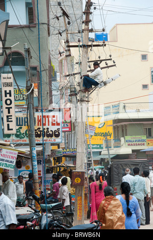 Elettricista indiano lavorando su un traliccio di elettricità per le strade di Puttaparthi, Andhra Pradesh, India Foto Stock