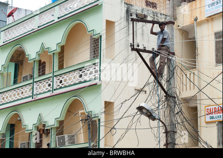 Elettricista indiano lavorando su un traliccio di elettricità per le strade di Puttaparthi, Andhra Pradesh, India Foto Stock