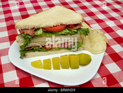 Blt panino tagliato a metà impilati su una piastra bianca con chip e sottaceti Foto Stock