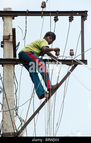 Elettricista indiano lavorando su un traliccio di elettricità per le strade di Puttaparthi, Andhra Pradesh, India Foto Stock