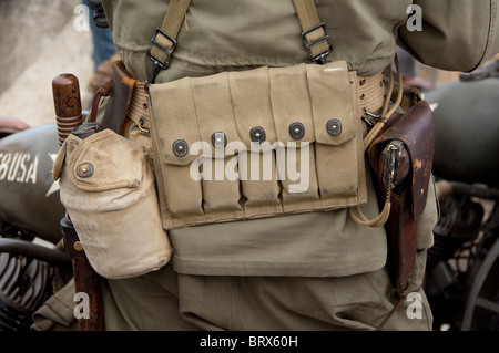 Francia, Normandia, Arromanches. Uomo in noi vintage uniforme con cinghia di munizioni e la pistola, nella parte anteriore del motociclo. Foto Stock