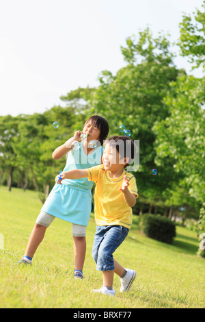Un ragazzo e una ragazza soffia bolle di sapone Foto Stock