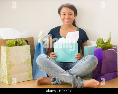 Sorridente razza mista ragazza adolescente circondato da borse per lo shopping Foto Stock