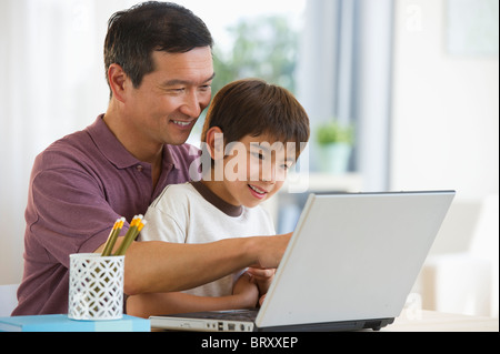 Sorridente padre e figlio utilizzando laptop Foto Stock