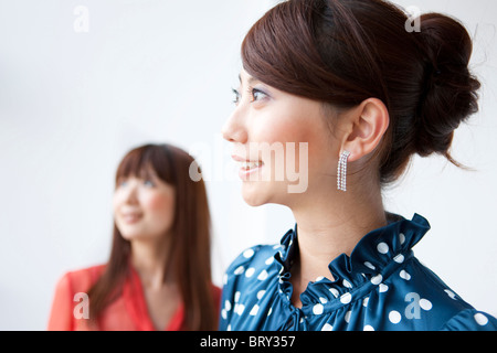 Due giovani donne a sorridere e a guardare lontano, sfondo bianco di messa a fuoco del differenziale Foto Stock