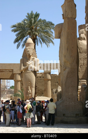 Il colosso di Ramesse II nel primo cortile del tempio di Karnak di Amon di Tebe, Luxor Egitto con gruppo di turisti rivolto lontano Foto Stock