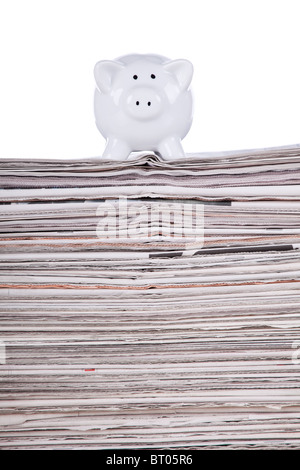 Piggybank sopra una pila di giornale (messa a fuoco selettiva) Foto Stock