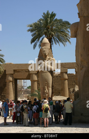 Il colosso di Ramesse II nel primo cortile del tempio di Karnak di Amon di Tebe, Luxor Egitto con gruppo di turisti rivolto lontano Foto Stock