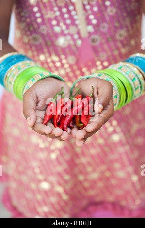 Indian ragazza con peperoncino rosso in mani a tazza Foto Stock