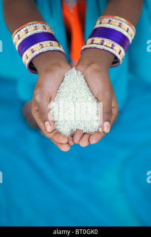 Ragazza indiana tenendo il riso crudo nelle sue mani a tazza. India Foto Stock