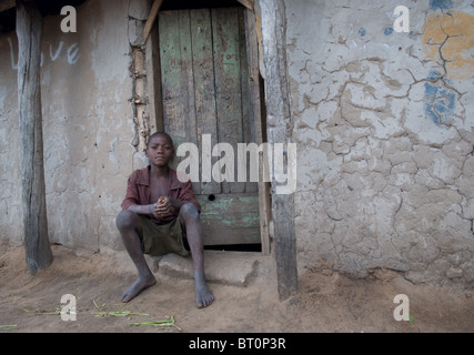 Ritratto di un ragazzo adolescente seduto fuori casa sua nel villaggio dello Zambia. Foto Stock