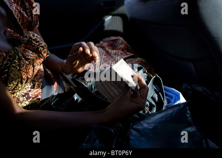 La donna in auto lo scambio di denaro sulla strada Freetown Sierra Leone Africa occidentale Foto Stock