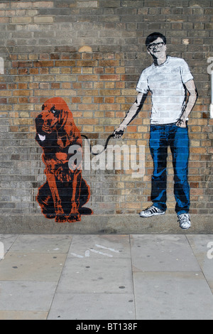 Uomo con cane stencil graffiti banksy stile, shoreditch Londra Foto Stock