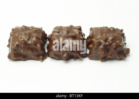 Fila di cubetti di cioccolato con dadi su sfondo bianco Foto Stock