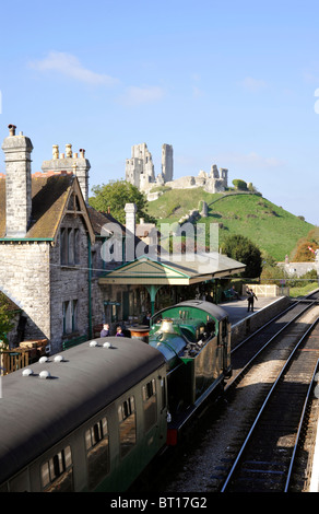 Treno a vapore alla stazione di corfe Corfe Castle in background su conserve di swanage linea ferroviaria Foto Stock