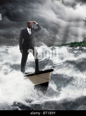 African American businessman Permanente al timone della barca sul mare in tempesta Foto Stock