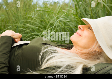 Sorridente Caucasian donna che dorme in erba Foto Stock