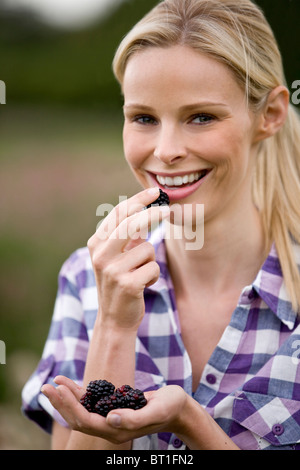 Una donna di mangiare appena raccolto more, all'aperto Foto Stock