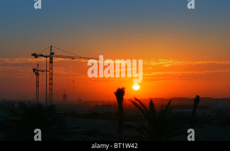 Gru da cantiere su arancione tramonto Cielo Foto Stock