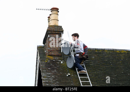 Un' Antenna e satellite engineer opera su un tetto. Foto di James Boardman Foto Stock