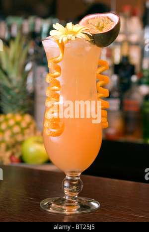 Cocktail tropicale in una hurricaneglass con un fiore, frutto della passione e abbinamenti di colore arancione Foto Stock