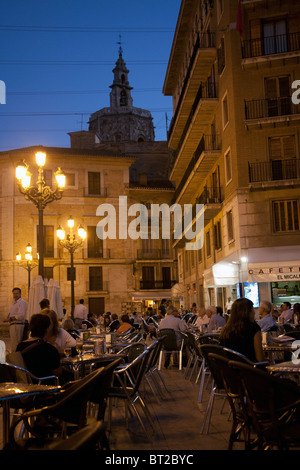 Le persone sedute a tavoli esterni nei caffè al tramonto su Plaza de la Virgen di Valencia Spagna Foto Stock