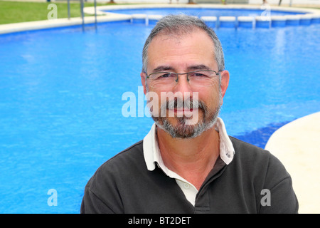 Senior uomo sorridente vacanza in blu piscina felice pensionato Foto Stock