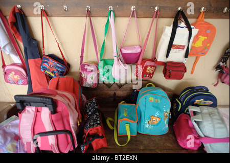 Kids' borse e zaini appesi a ganci in una scuola primaria Foto Stock