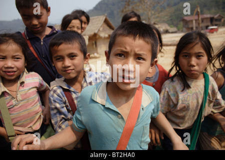 I ragazzi e le ragazze che frequentano una scuola elementare sono riuniti fuori dopo la rientranza in corrispondenza di una istituzione di apprendimento in Laos comunista. Foto Stock