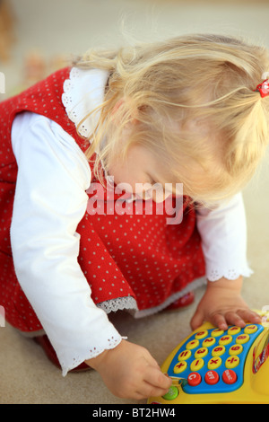 Capelli biondi 2 anno vecchia ragazza giocando con il giocattolo registratore di cassa Foto Stock