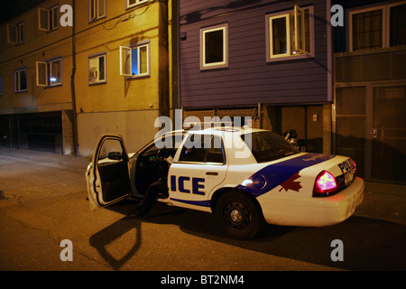 Cop seduto in una macchina della polizia in un vicolo a tarda notte, Vancouver, British Columbia, Canada Foto Stock