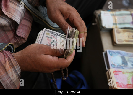 Un caricatore di denaro contando di dollari americani nel mercato in Iraq Foto Stock